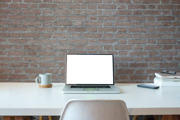 istock Laptop computer, coffee cup and book on white table. Blank display for product display or graphic montage. 1480703776