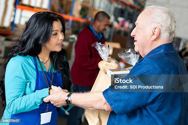 Volontariato Aiutando Uomo Anziano Con Generi Alimentari Presso Una Banca Del Cibo - Fotografie stock e altre immagini di Uomini anziani