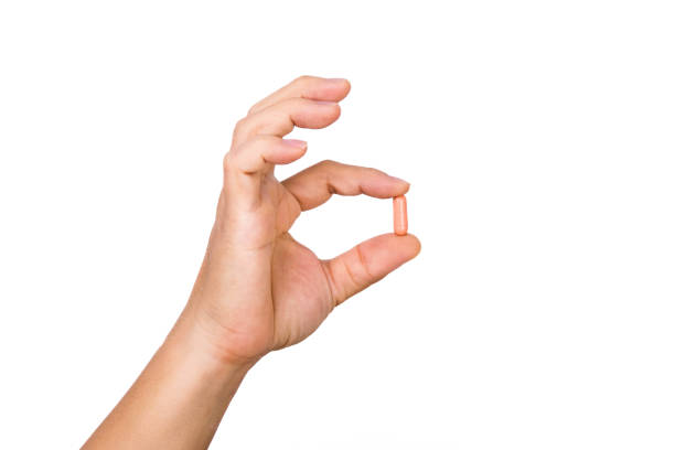 istock Hand holding a capsule or pill isolated on white background. 1480704741