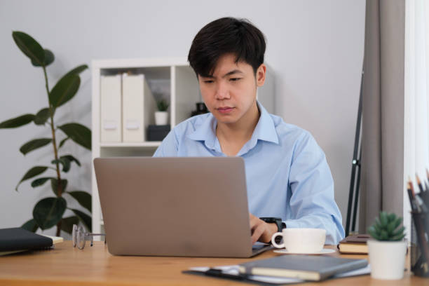 istock Smiling handsome asian man freelancer working with laptop computer. 1480704968