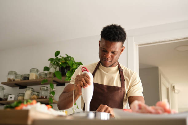 Young african man using a blender to prepare chicken mince.