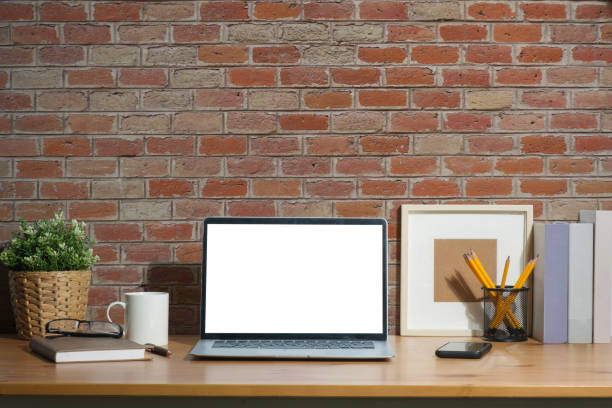 istock Laptop computer with empty screen, picture frame and  supplies on wooden desk. Stylish workplace. 1480706902