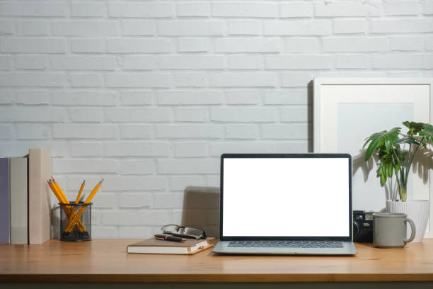 istock Front view of laptop computer with empty display, picture frame and stationery on wooden working desk. 1480715843