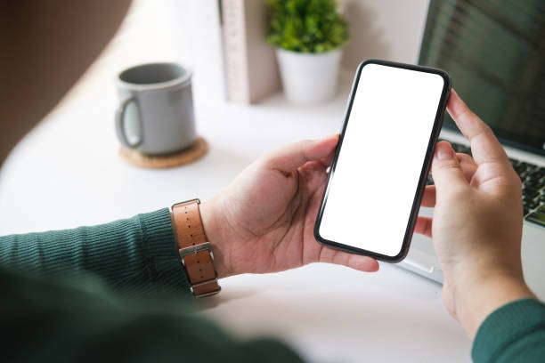 istock Man freelancer using smart phone at home office desk. Blank  screen for your text message or information content. 1480715978