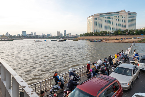 Phnom Penh,Cambodia-December 24th 2022:The Chroy Changvar Ferry takes passengers,with cars and motorbikes across the river to the eastern side,where the Sokha five star luxury hotel is lacated.