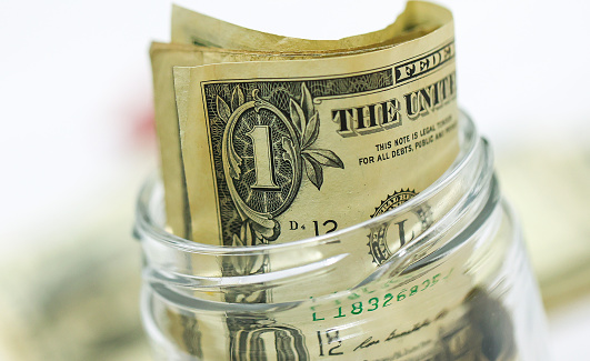 United States one dollar bills inside a glass jar in macro photography. Money saving concept.