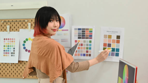 istock Portrait of young female designer using graphic tablet and working with color swatch samples at creative workstation. 1480725429