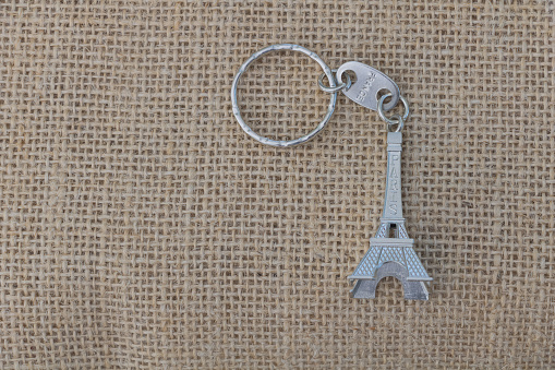 Eiffel Tower key on sackcloth background with copy space.