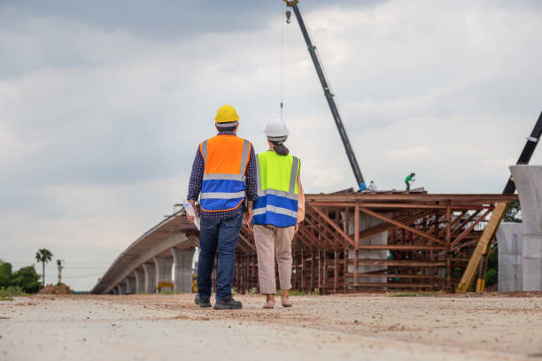 istock Female engineer and foreman worker checking project at building site, Engineer and builders in hardhats discussing on construction site, Teamwork concepts 1480729785