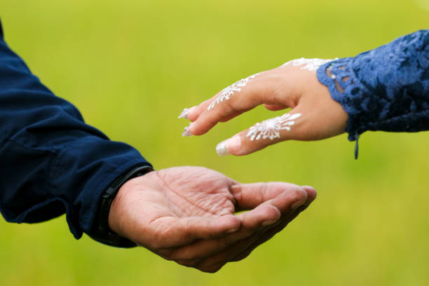Close up of man and woman holding hands in outdoor with green backgroundClose up of holding hands