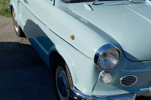 Photo of Front right of an old german classic car . Particular view of right front light, tires and shiny chrome bumper