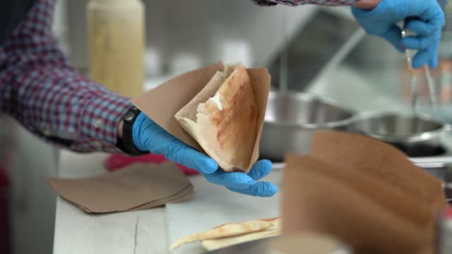Cook preparing traditional Greek pita souvlaki sandwich in a fast food restaurant