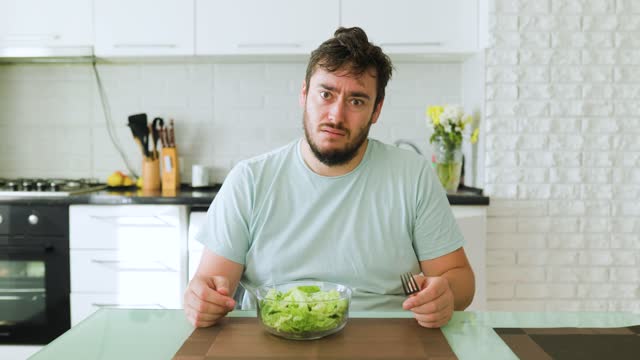 unhappy man at home is forced to eat salad