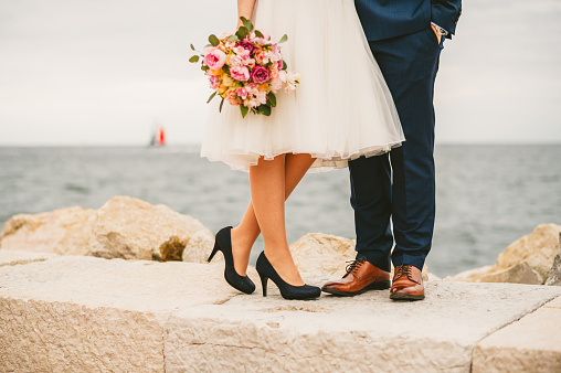 Bride and groom standing close together with the wedding bouquet on a pier