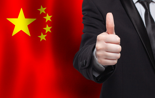 Chinese concept. Businessman showing thumb up on the background of flag of China