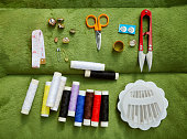 Sewing kit flat lay including spools of thread, scissors, measuring tape, buttons, needles