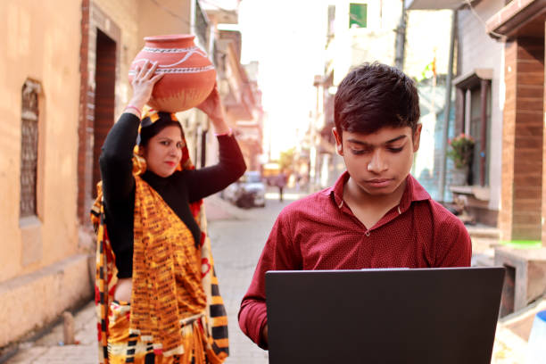 Indian schoolboy using laptop outdoors in street stock photo