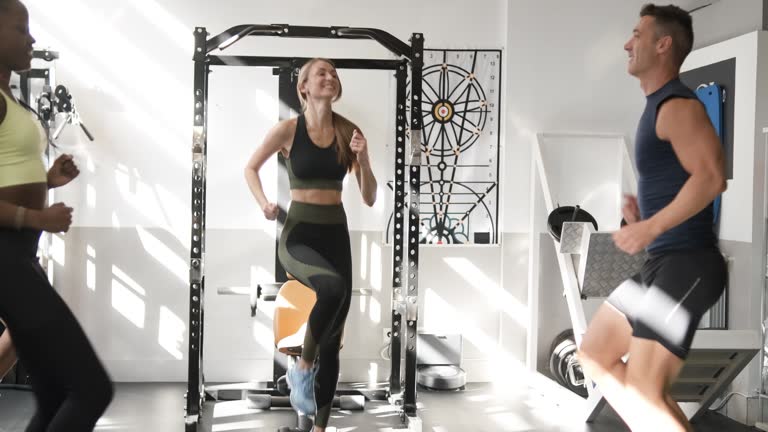 Four people and a coach are seen training in a gym in a guided cardio class