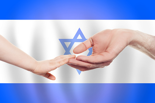Izraeli baby and parent hands on the background of flag of Izrael Help, aid, support, charity concept