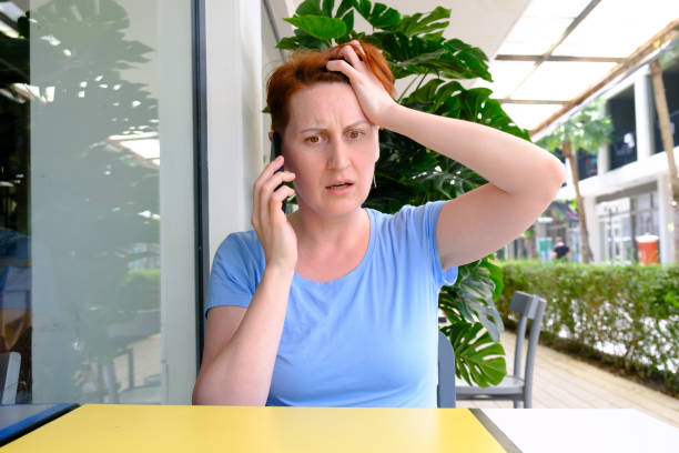 une femme aux cheveux courts tient un smartphone et crie furieusement dans le micro - furiously photos et images de collection
