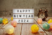 Happy New Year 2024 text on lightbox on wooden background