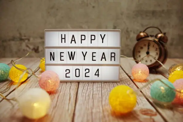 Happy New Year 2024 text on lightbox on wooden background
