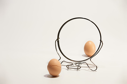 brown and broken eggs reflected in the mirror on the white background.