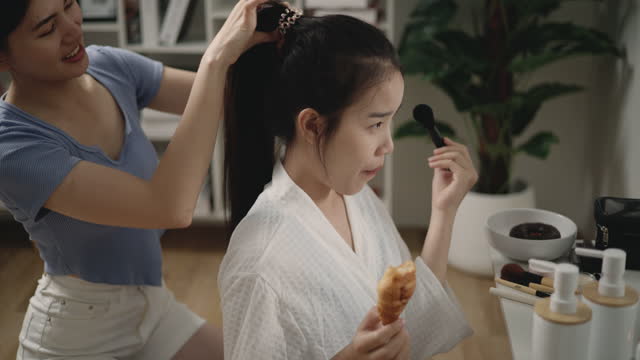A beautiful young Asian woman applying makeup in front of the mirror