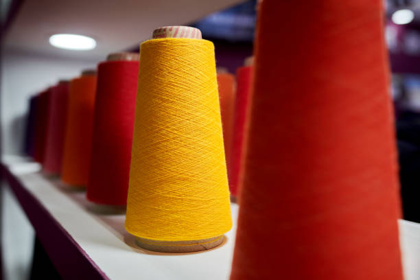 Red & Orange Cotton Yarn Spindles Side view of red & orange cotton yarn spindles. cotton mill stock pictures, royalty-free photos & images