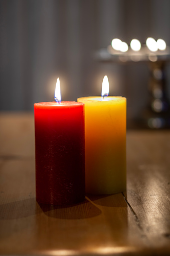 One red and one yellow candle on a coffee table at night