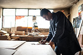 Young carpenter making annotations on his clipboard at carpentry