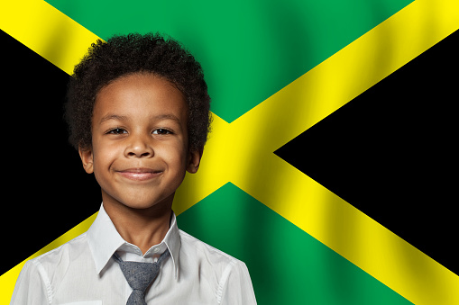 Jamaican kid boy on flag of Jamaica background. Education and childhood concept