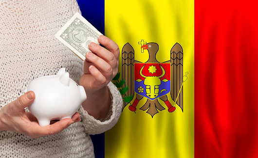 Moldovan woman with money bank on the background of Moldova flag. Dotations, pension fund, poverty, wealth, retirement concept