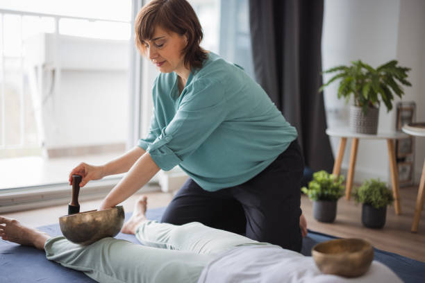 massaggiatrice con campane tibetane durante il massaggio shiatsu - shiatsu massaging alternative therapy zen like foto e immagini stock