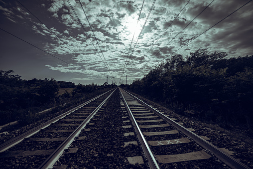 Dark landscape with diminishing perspective of traintracks and cloudscape