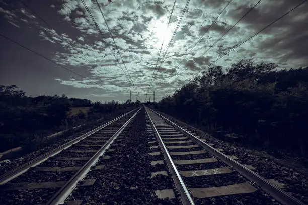 Dark landscape with diminishing perspective of traintracks and cloudscape
