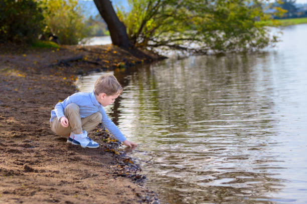 istock Boy kneels by a lake 1480757665
