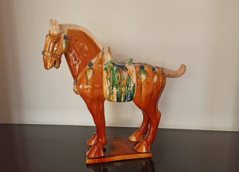 A closeup picture of a Chinese Ceramic colourful Tang Horse toy against a white background