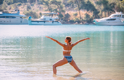 Young Woman Practicing Yoga in the Sea at the Beach