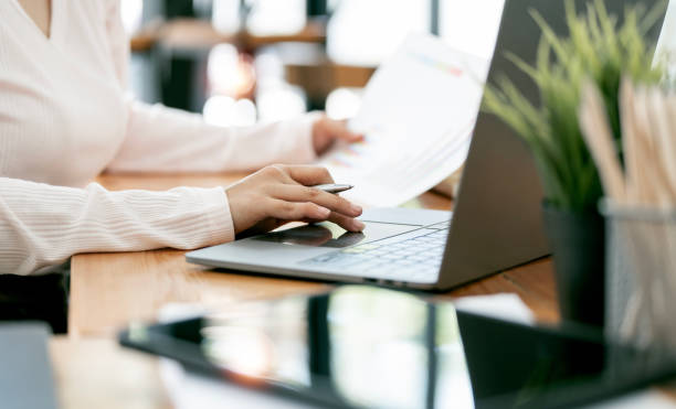 istock Cropped shot of young female freelancer or accountant working on laptop computer and document, sitting at her desk in open office. 1480773549