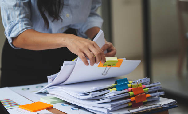 mano d'affari che lavorano in pile di file cartacei per la ricerca e il controllo di documenti non finiti su cartelle di carte - bureaucracy foto e immagini stock