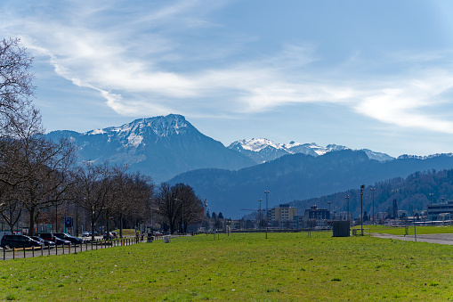 Scenic landscape with Swiss Alps and farm buildings in the background seen from Allmend City of Luzern, Canton Lucerne, on a sunny spring day. Photo taken March 22nd, 2023, Lucerne, Switzerland.