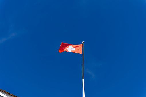 Swiss flag waving at local mountain Gütsch, Canton Luzern, on a sunny spring day. Photo taken March 22nd, 2023, Lucerne, Switzerland.