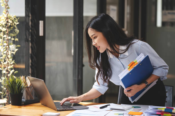 istock young businesswoman working with documents in office, standing at work table with laptop, serious employee checking financial report, project statistics, reading correspondence 1480786710