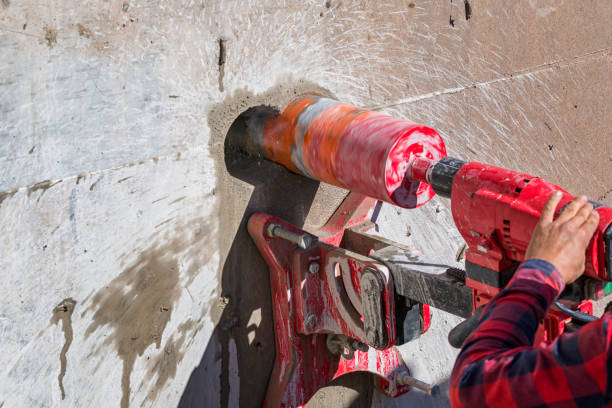 Worker is drilling to concrete wall with core drill machine. Core drills used in metal are called annular cutters. Core drills used for concrete and hard rock generally use industrial diamond grit. el trabajador está perforando la pared de concreto con la máquina de perforación de núcleo. los taladros de núcleo utilizados en metal se llaman cortadores anulares. los taladros de núcleo utilizados para concreto y roca dura generalmente usan grano