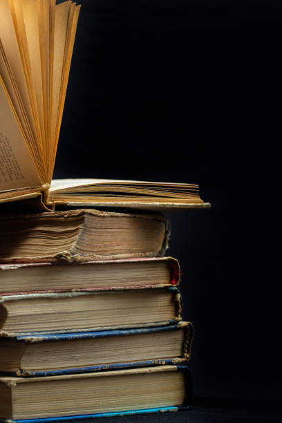istock stack of old books with opened one on top on dark background. Old books in the library. Bookshelf shop. Knowledge publications, literature. Bookish bookstore, bookstore 1480788033