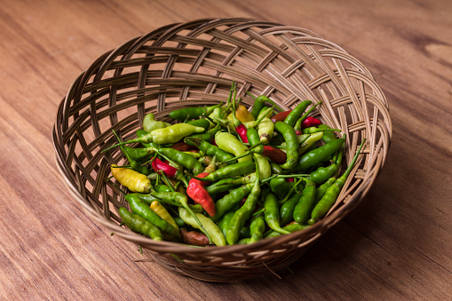 Photograph of chili pepper on the basket with wood background