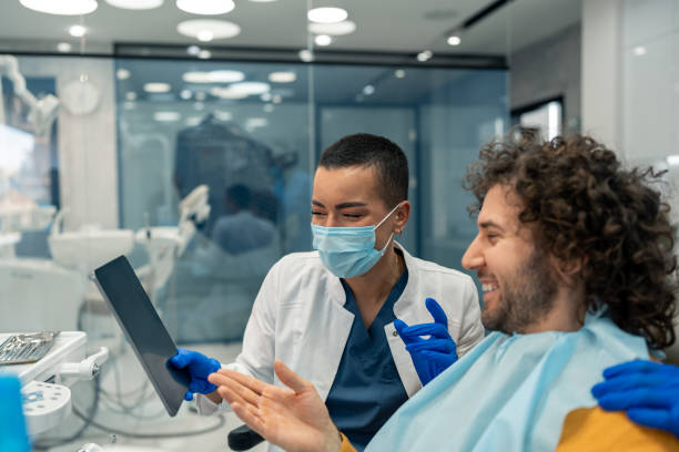 歯科医院でデジタルタブレットを使用する陽気でフレンドリーな歯科医と患者 - dentist dentists chair men confidence ストックフォトと画像