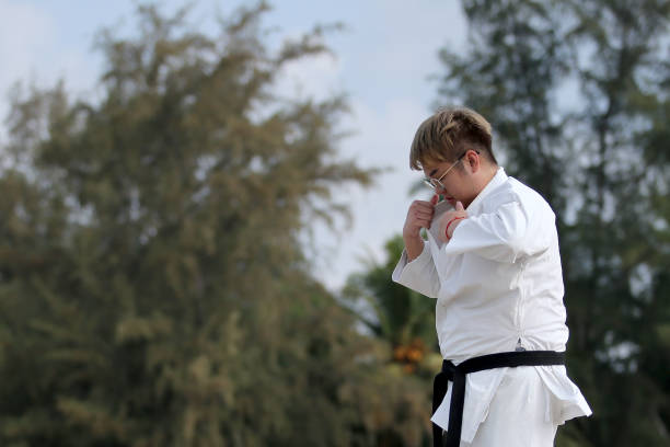 An Asian man is adjusting taekwondo uniform by the beach.