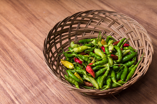 Photograph of chili pepper on the basket with wood background